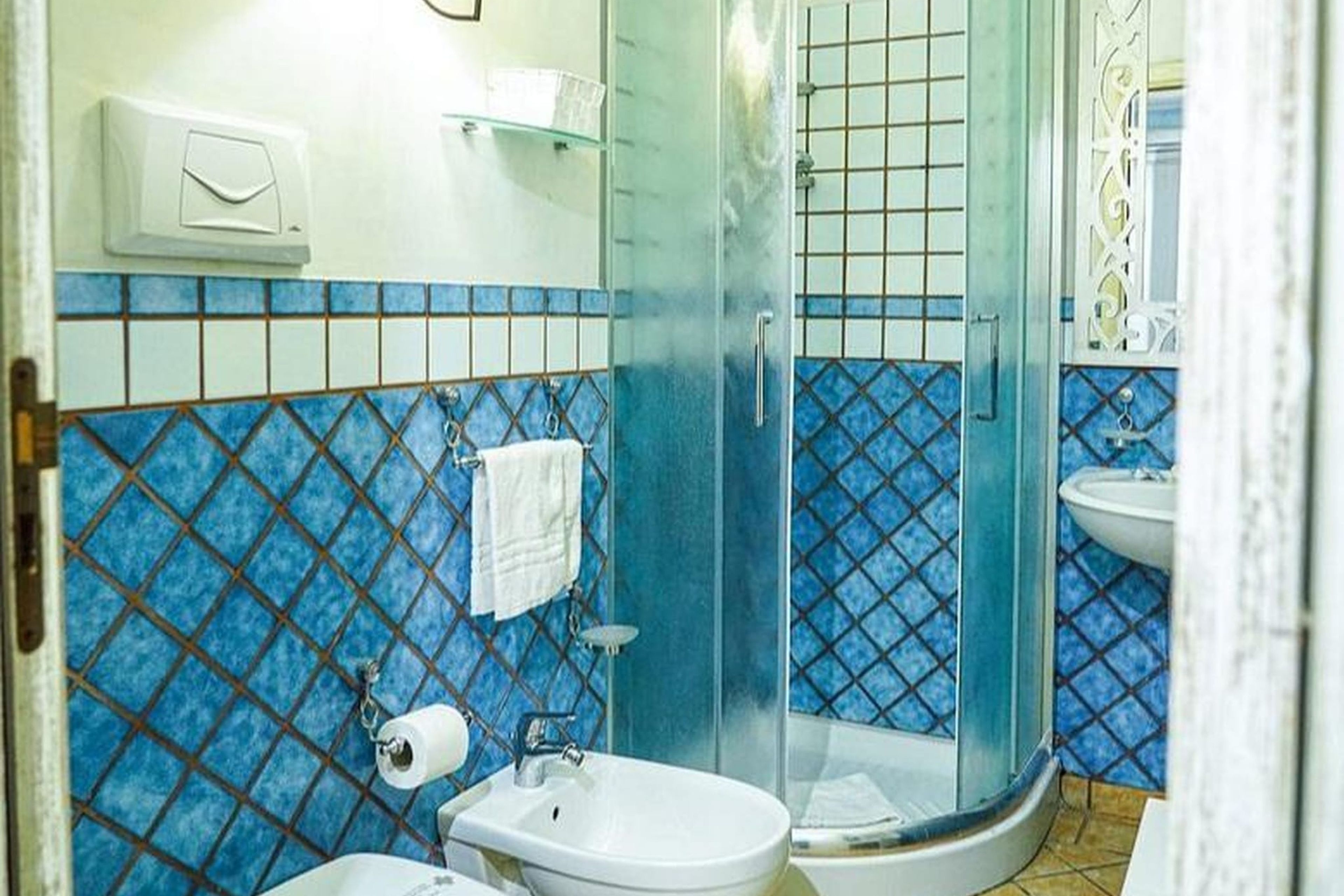 Un baño con cabina de ducha de vidrio, un lavamanos blanco y un inodoro.