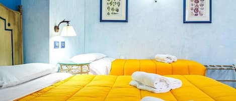 A hotel room with two beds, a bedside table, a lamp, and two framed pictures on the wall.