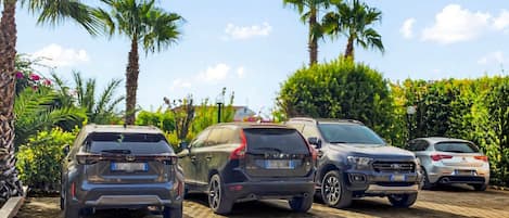 A parking lot with four cars and palm trees in the background.