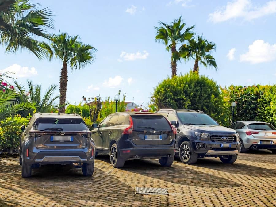 A parking lot with four cars and palm trees in the background.