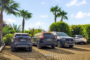 Un parking avec quatre voitures et des palmiers en arrière-plan.