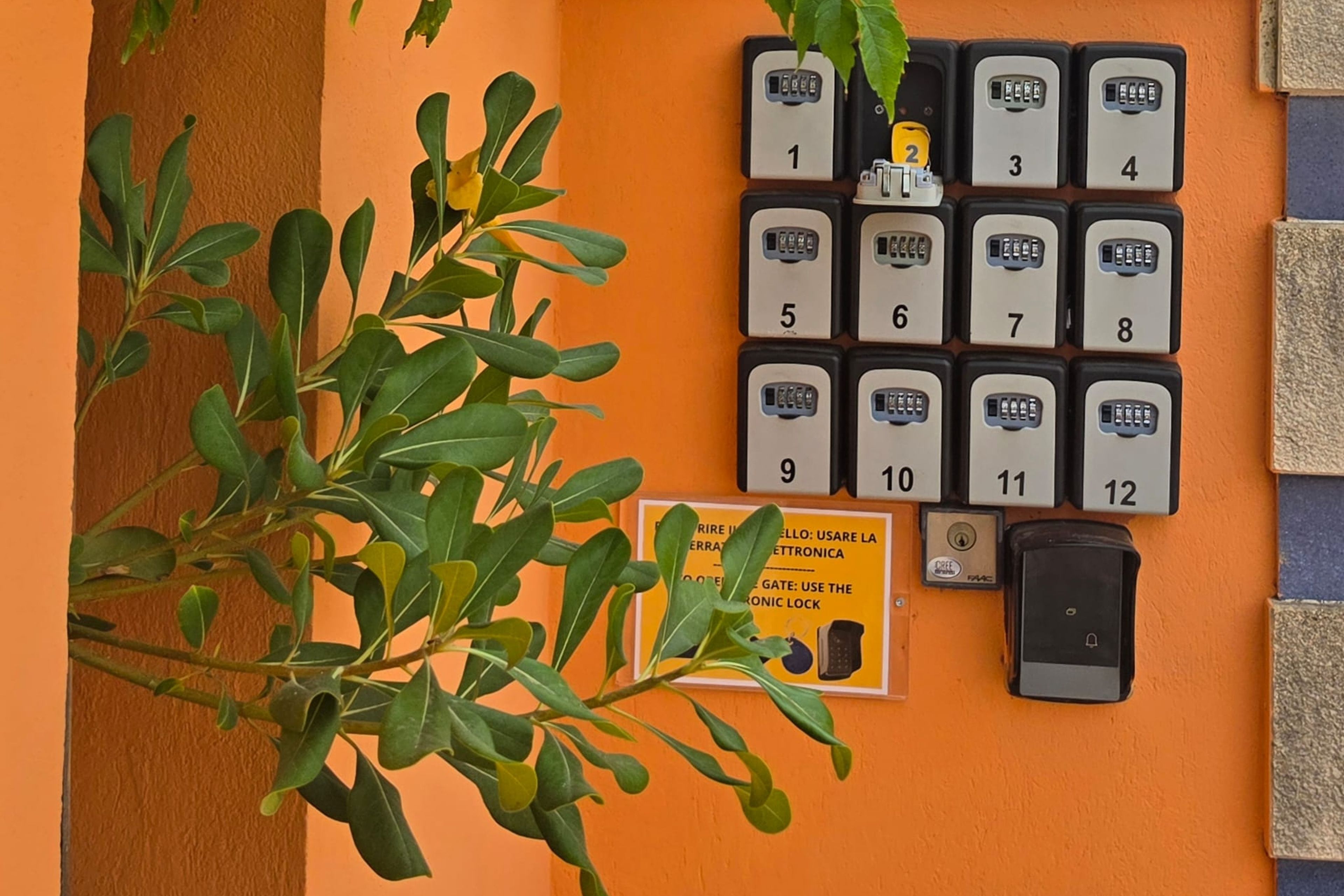 Een rij genummerde hotelkamer sleutels aan een muur, een bord met de instructie om het elektronisch slot te gebruiken, en een deurbel.