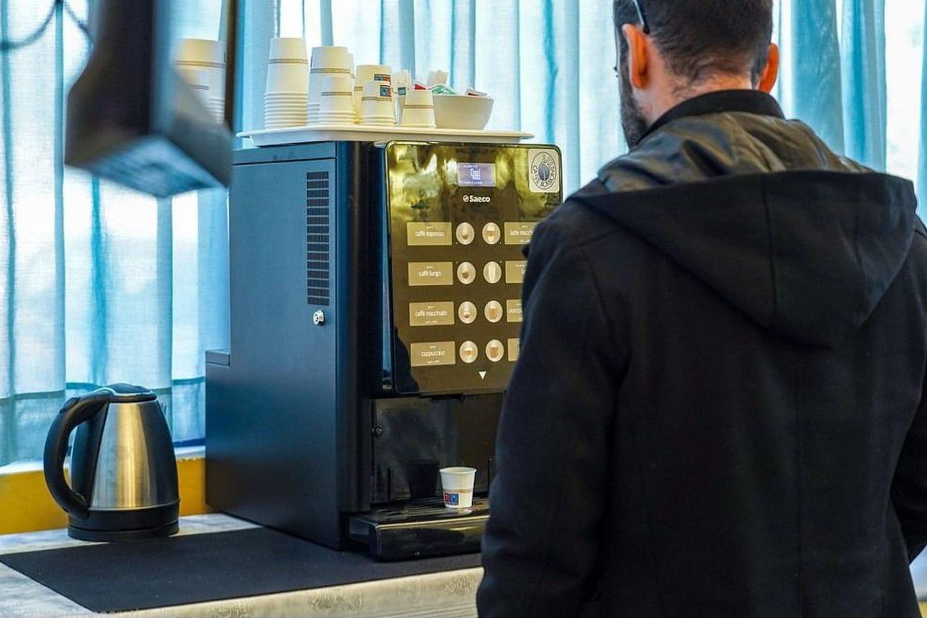 Una cafetera con pantalla digital y una taza de café sobre la encimera.
