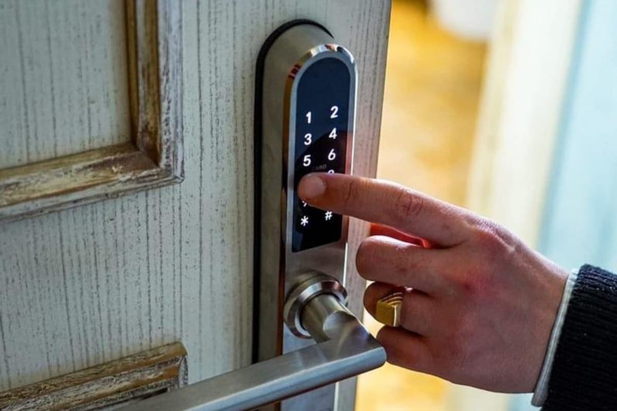 A hand pressing a numeric keypad on a door lock.