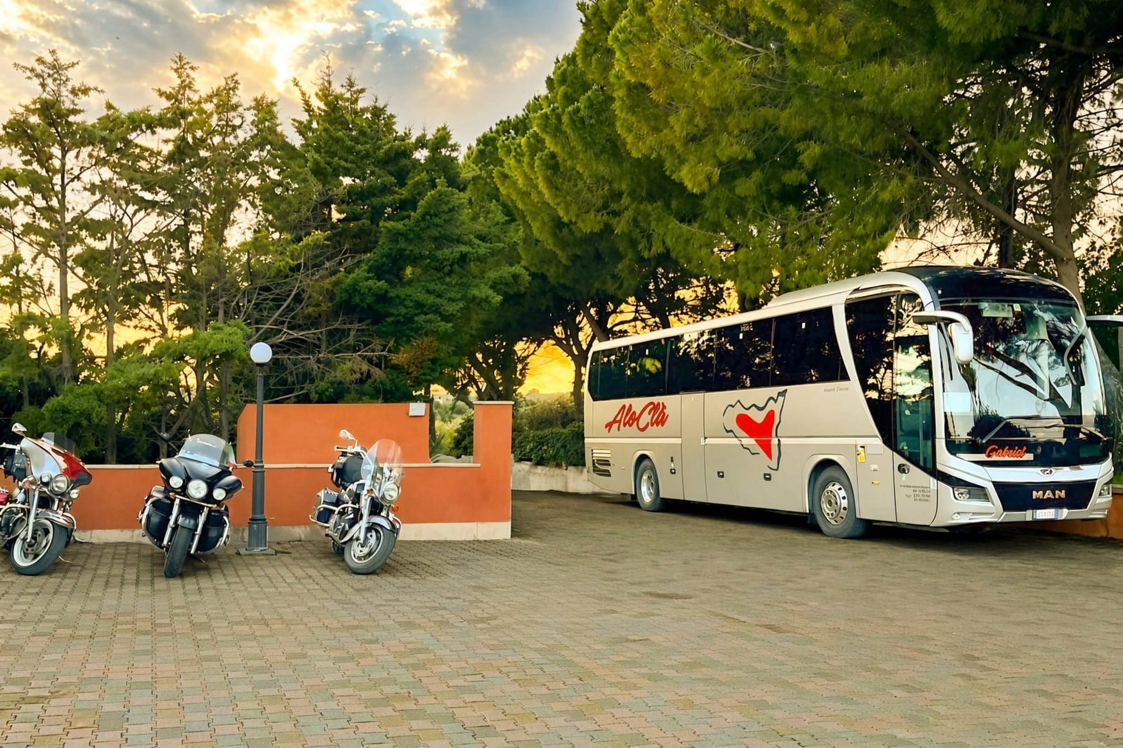 A bus parked in a paved area with trees in the background.