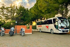 A bus parked in a paved area with trees in the background. - Motel - Hotel Nautico Pozzallo (Pozzallo)