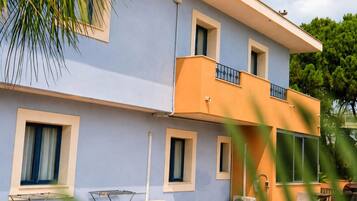 A two-story building with a balcony, windows, and outdoor furniture.
