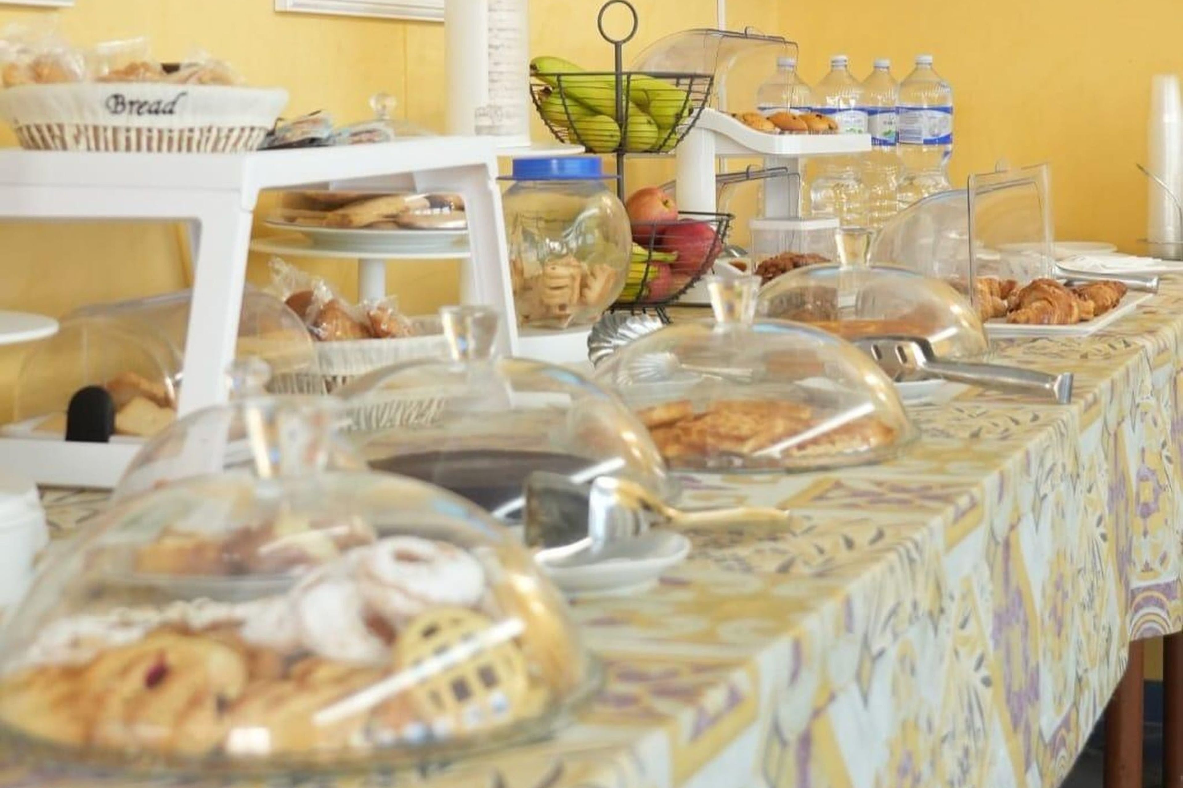Uma mesa de buffet com alimentos cobertos e uma cesta de pão.