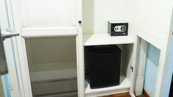 Una habitación pequeña con una puerta blanca, un mueble de almacenaje negro y un estante blanco con una radio.