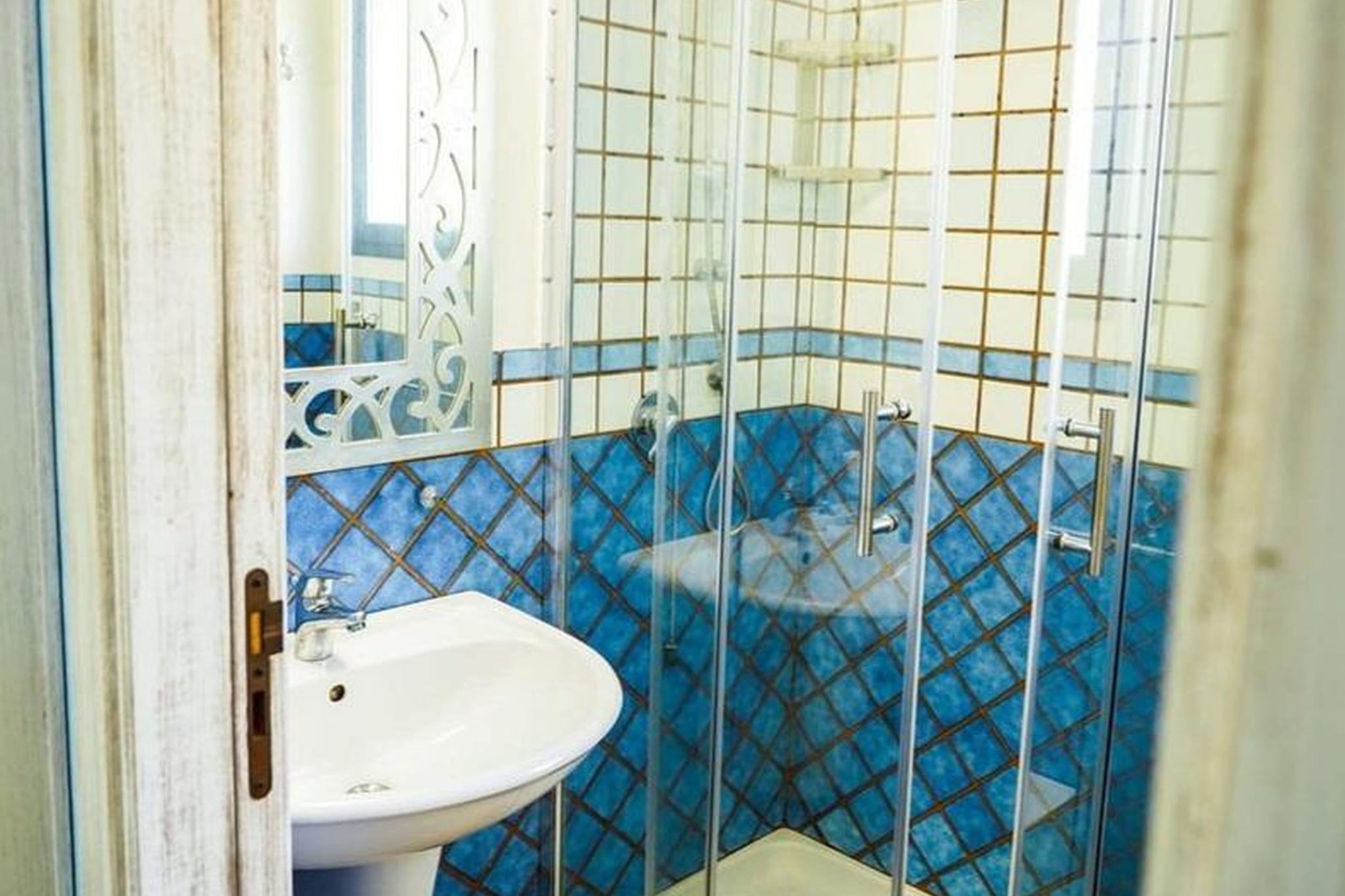 A bathroom with a white sink, a shower enclosure, and blue patterned tiles.