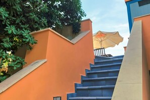 A staircase with a blue handrail and orange walls, leading to a covered area with an umbrella. - Motel - Hotel Nautico Pozzallo (Pozzallo)