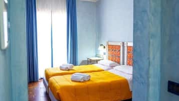 Habitación de hotel con dos camas, un escritorio y una ventana con cortinas.
