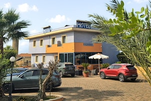 Un hotel con insegna, auto parcheggiate e posti a sedere all'aperto.
