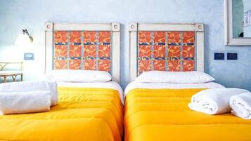 Habitación de hotel con dos camas, cada una con cabecera estampada y ropa de cama amarilla.