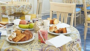 A breakfast setting with various food items, cups, and a table with a floral tablecloth. - Motel - Hotel Nautico Pozzallo (Pozzallo)