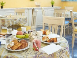 Una colazione con diversi cibi, tazze e un tavolo con una tovaglia floreale.