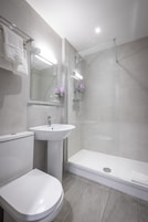 Uma casa de banho moderna com sanita, lavatório e cabine de duche em vidro.