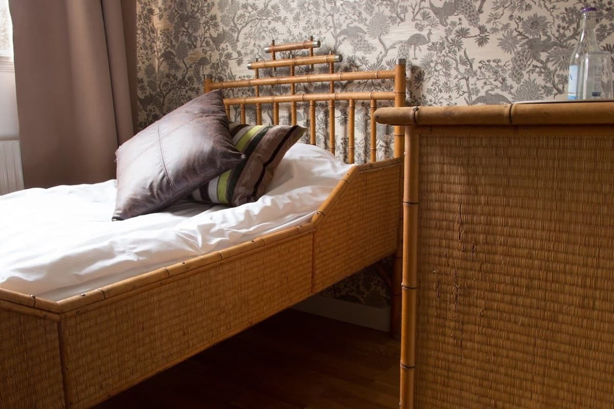 A single bed with a wooden frame and a white mattress, accompanied by a headboard and a bedside table.