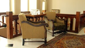A room with two upholstered chairs, a wooden table, and a patterned rug.