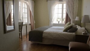 A bedroom with a bed, a chair, a desk, and a lamp.