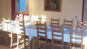 Un'area pranzo con sedie e tavoli in legno, una finestra vista e un quadro appeso al muro.