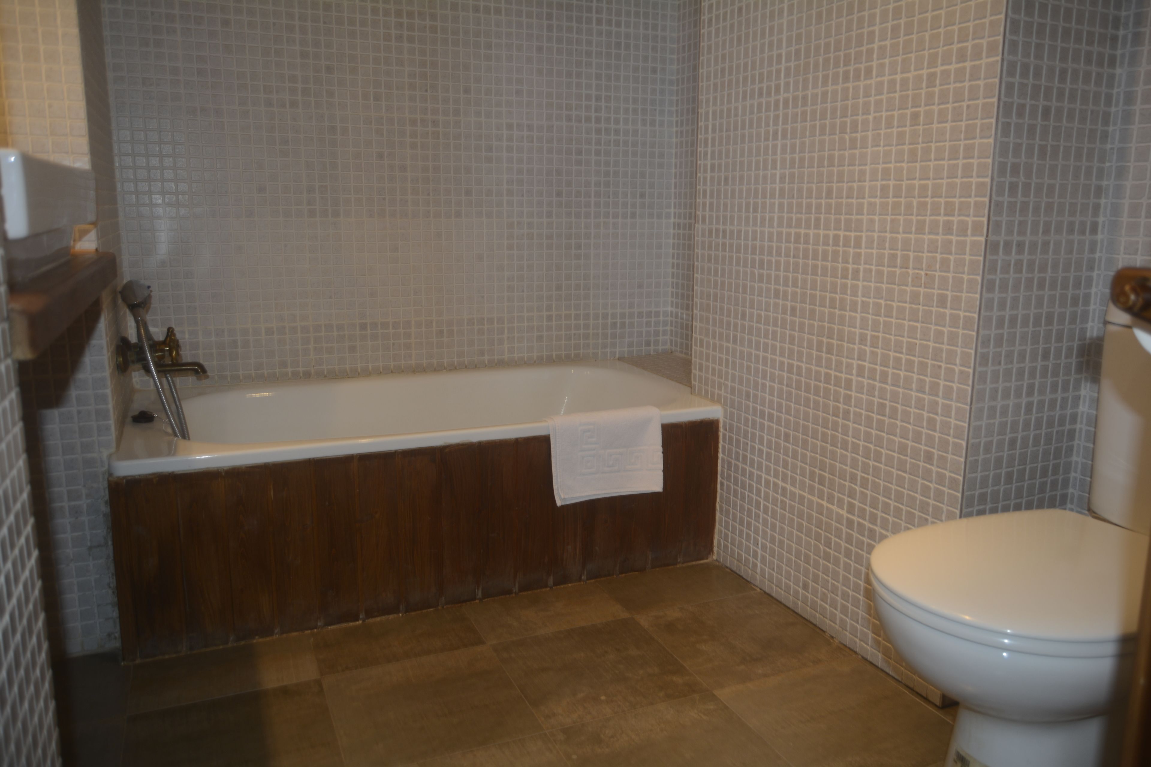 Ein Badezimmer mit Badewanne, Toilette und Fliesenwänden.