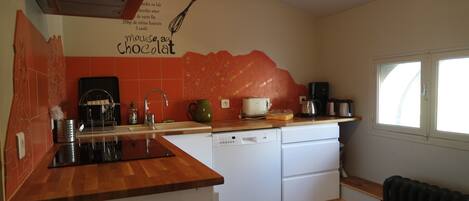 A kitchen with a wooden countertop, white dishwasher, and a wall-mounted coffee maker.