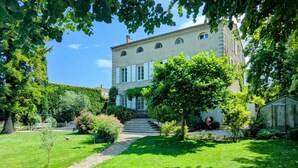 A large, historic building with a symmetrical facade, a central staircase, and a well-maintained garden with a variety of plants and a small pond. - Villa Rhôna (Andancette)