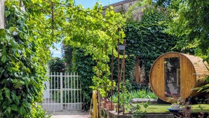 A rustic wooden structure in a lush garden with a gravel path leading to a white gate. - Villa Rhôna (Andancette)
