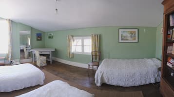 Una habitación con dos camas, un escritorio, una silla, una estantería y una ventana con cortinas.
