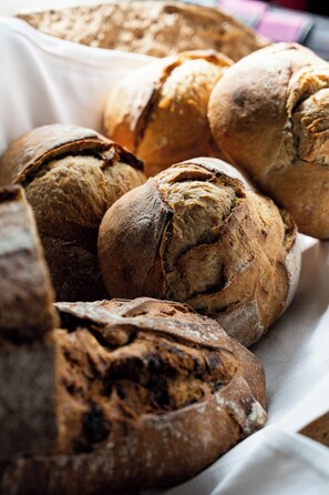 A variety of breads with a rustic appearance, including a loaf with a crusty exterior and a torn top.