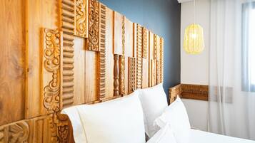 Un dormitorio con cabecera de madera con tallas elaboradas, cama blanca con almohadas y lámpara colgante.