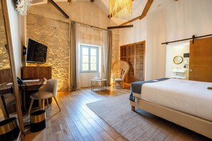 A bedroom with a bed, a desk, a chair, a small table, and a wardrobe.