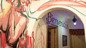 Un intérieur agrémenté d’une fresque murale, d’une enseigne d’accueil et d’une porte en bois.