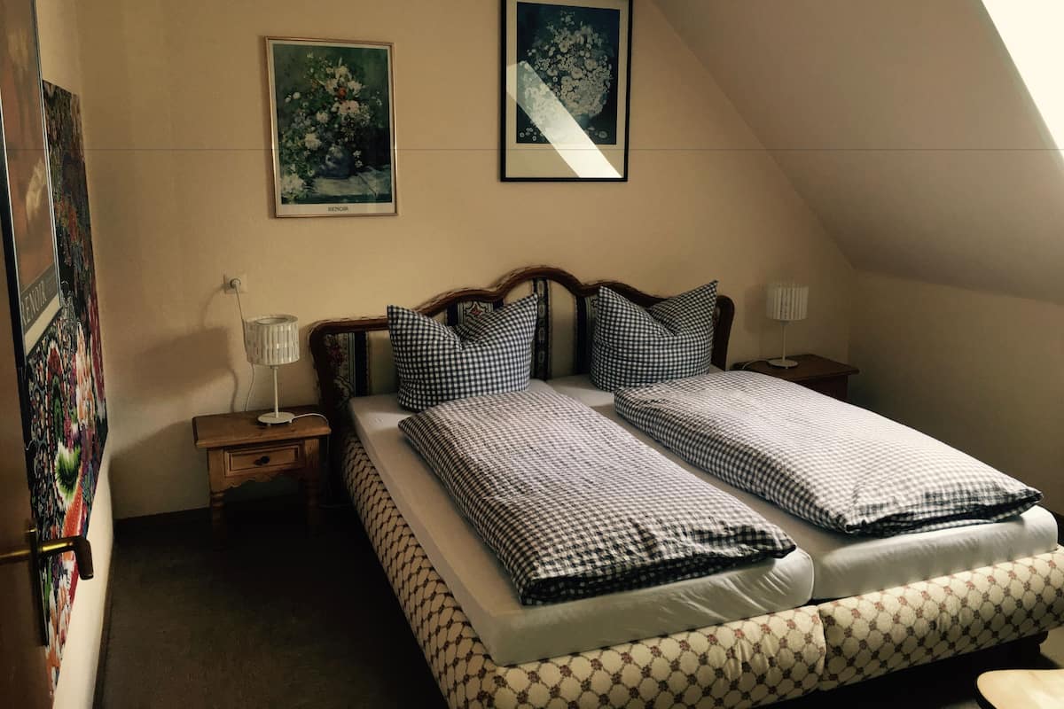 Ein Schlafzimmer mit einem Bett, zwei Nachttischen, einer Lampe und zwei gerahmten Bildern an der Wand.