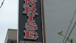 A vertical sign with the word "SUNRISE" in large, illuminated letters, indicating a hotel or establishment named SUNRISE. - Sunrise Guesthouse (Quy Nhon Nam)