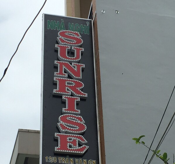 A vertical sign with the word "SUNRISE" in large, illuminated letters, indicating a hotel or establishment named SUNRISE. - Sunrise Guesthouse (Quy Nhon Nam)