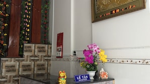 A reception area with a stone wall, a clock, a framed artwork, and a 'Lê Tân Reception' sign. - Sunrise Guesthouse (Quy Nhon Nam)