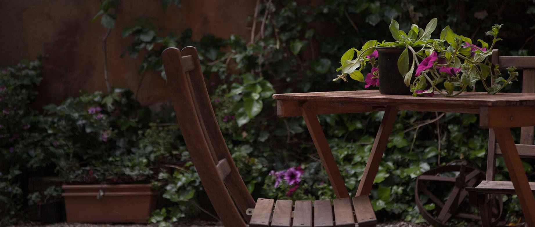 Une table en bois, agrémentée d’une plante en pot et accompagnée d’une chaise, dans un décor de jardin.