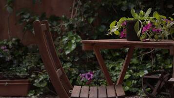 Une table en bois, agrémentée d’une plante en pot et accompagnée d’une chaise, dans un décor de jardin.