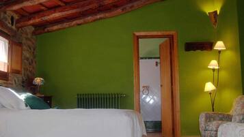 A bedroom with a bed, a chair, a lamp, and a door leading to a bathroom.