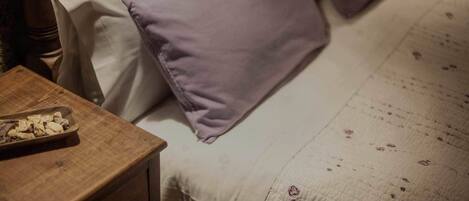 A bed with a floral-patterned bedspread and two pillows, one purple and one white.