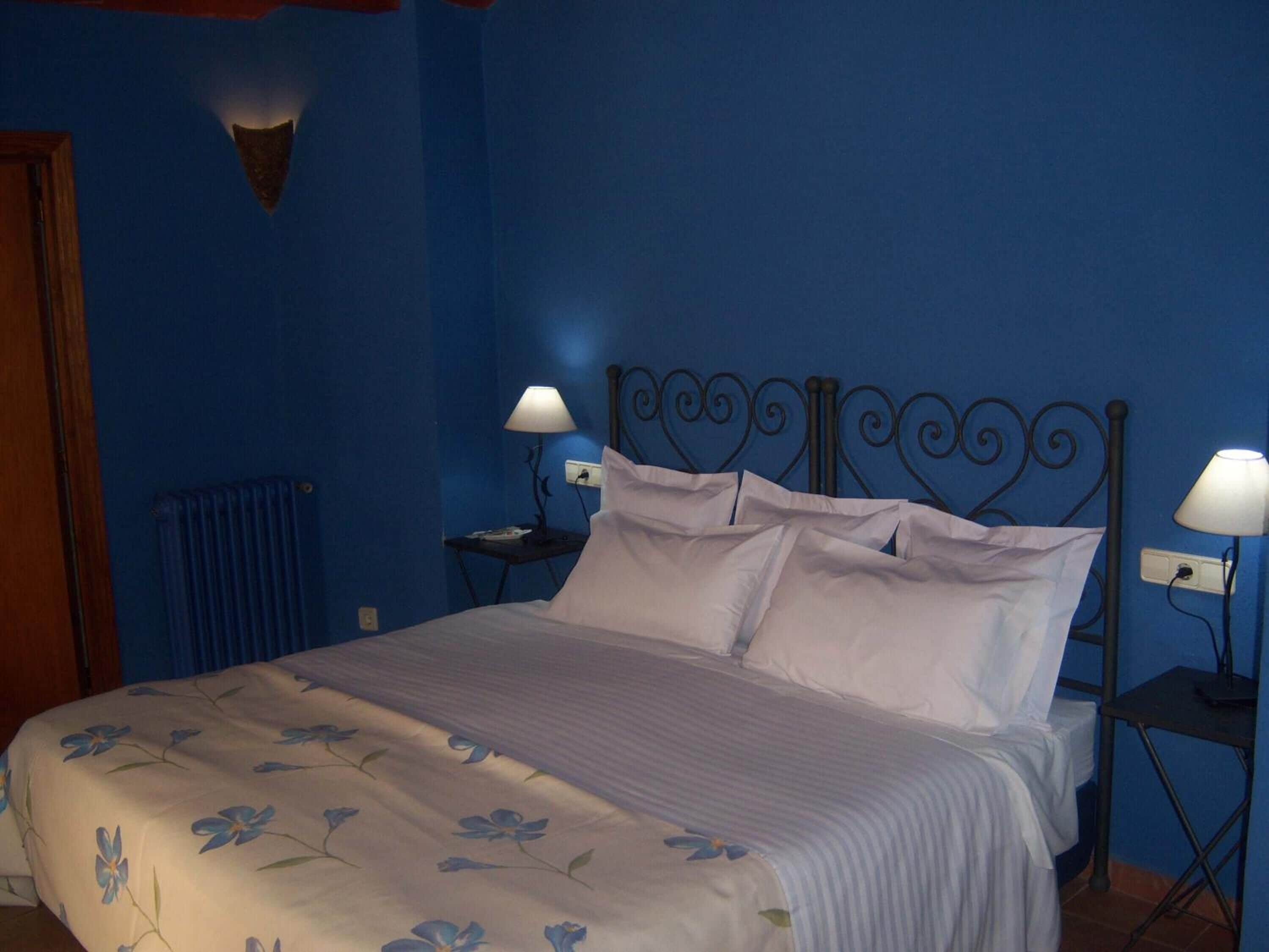A bedroom with a bed, two bedside tables, and a wall-mounted light fixture.
