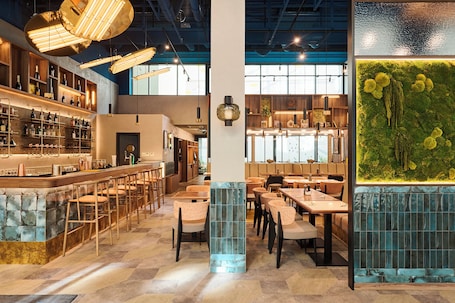 A modern bar area with wooden shelves, bar stools, and pendant lighting.