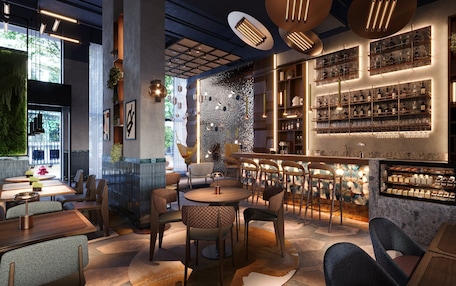 Un área de bar moderna con asientos, una barra y estantes llenos de botellas.