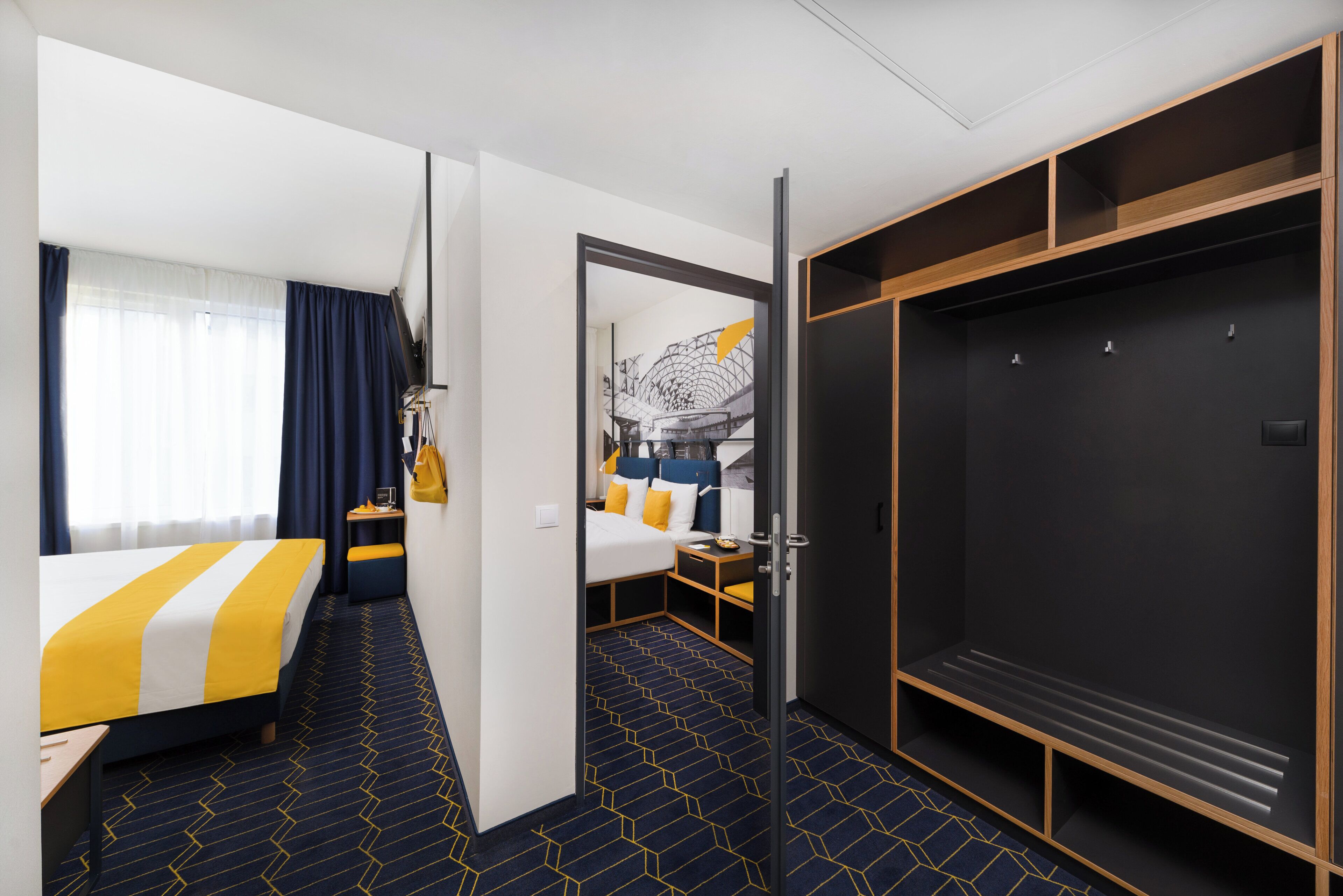 Camera d'albergo con un letto, una scrivania, un armadio e un bagno visibile attraverso una porta aperta.