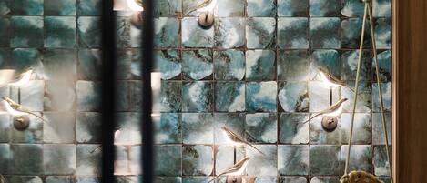 A tiled wall with bird-shaped light fixtures and a hanging chair.