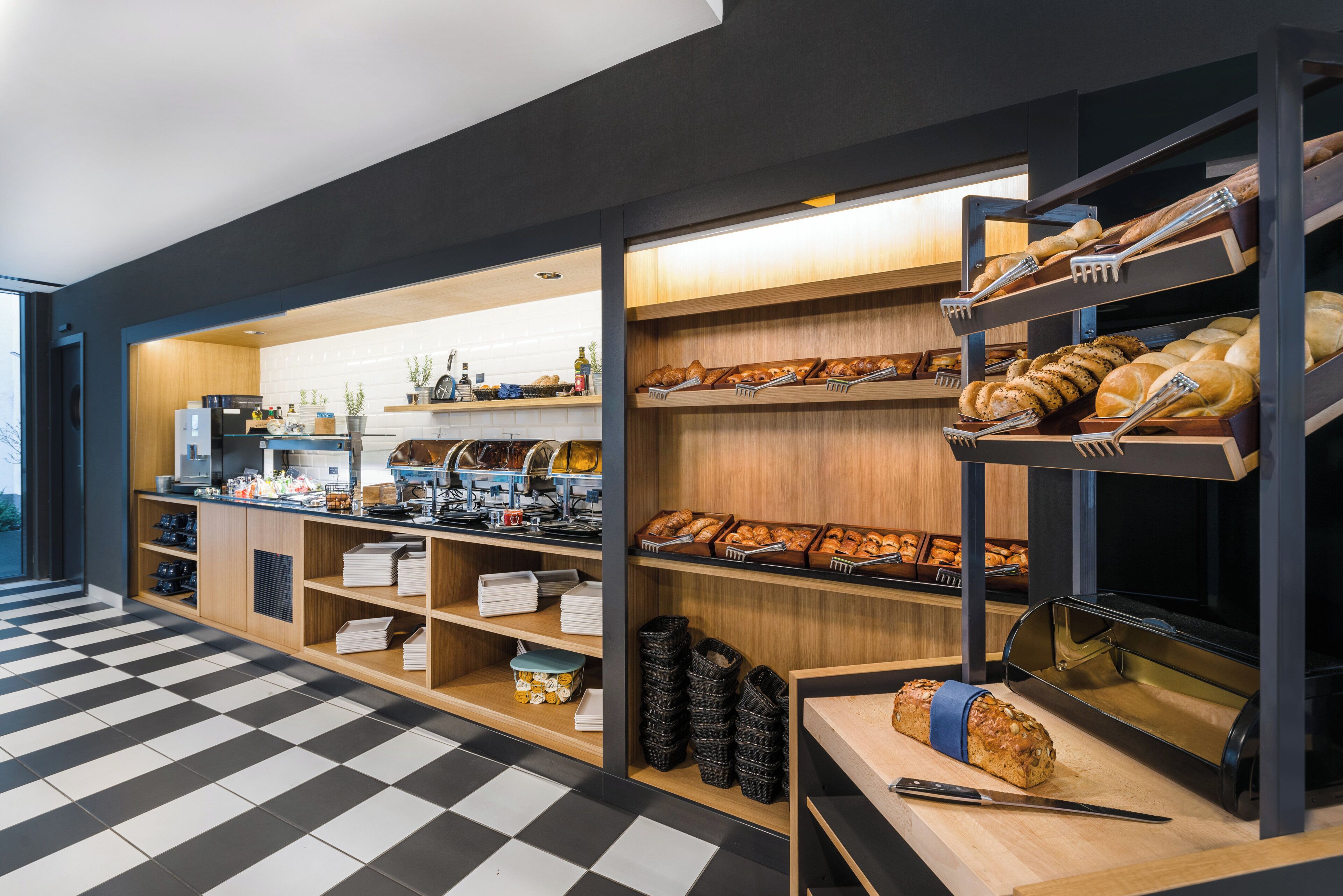 A bakery section with shelves of bread and pastries, a coffee station, and a checkered floor.