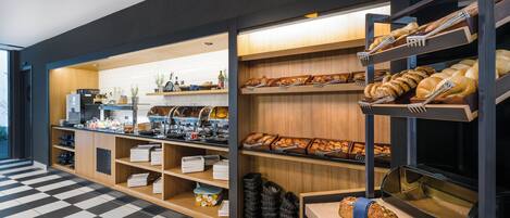 A bakery section with shelves of bread and pastries, a coffee station, and a checkered floor.