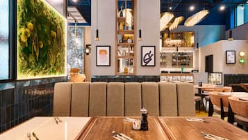 Un restaurante con pared verde, muebles de madera y una zona de bar.